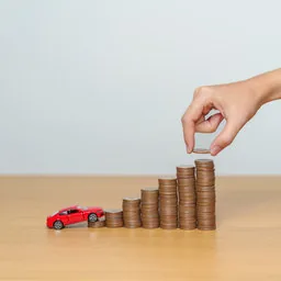 Münzstapel und Spielzeugauto: das eigene Fahrzeug finanzieren